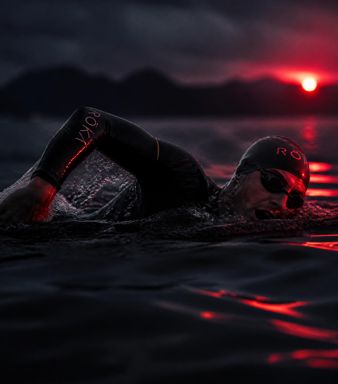 Triathlete swimming in open water at dawn